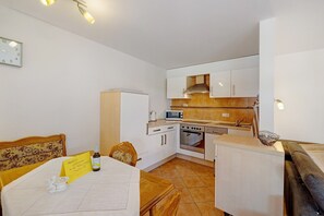 A compact kitchen with white cabinets, a microwave, an oven, and a sink.