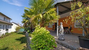 A garden with a statue, a palm tree, and a potted plant.
