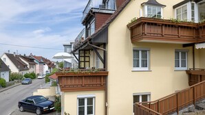 A residential building with a balcony, a staircase, and a parked car. - Apartment 'Weinberg' with Balcony (Meersburg)