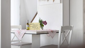 A table with a bottle, a card, and a vase with flowers. - Apartment 'Seeblick' with balcony, mountain and lake view (Meersburg)