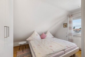 Une chambre à coucher avec un lit, une petite table et une fenêtre donnant sur un beau paysage.