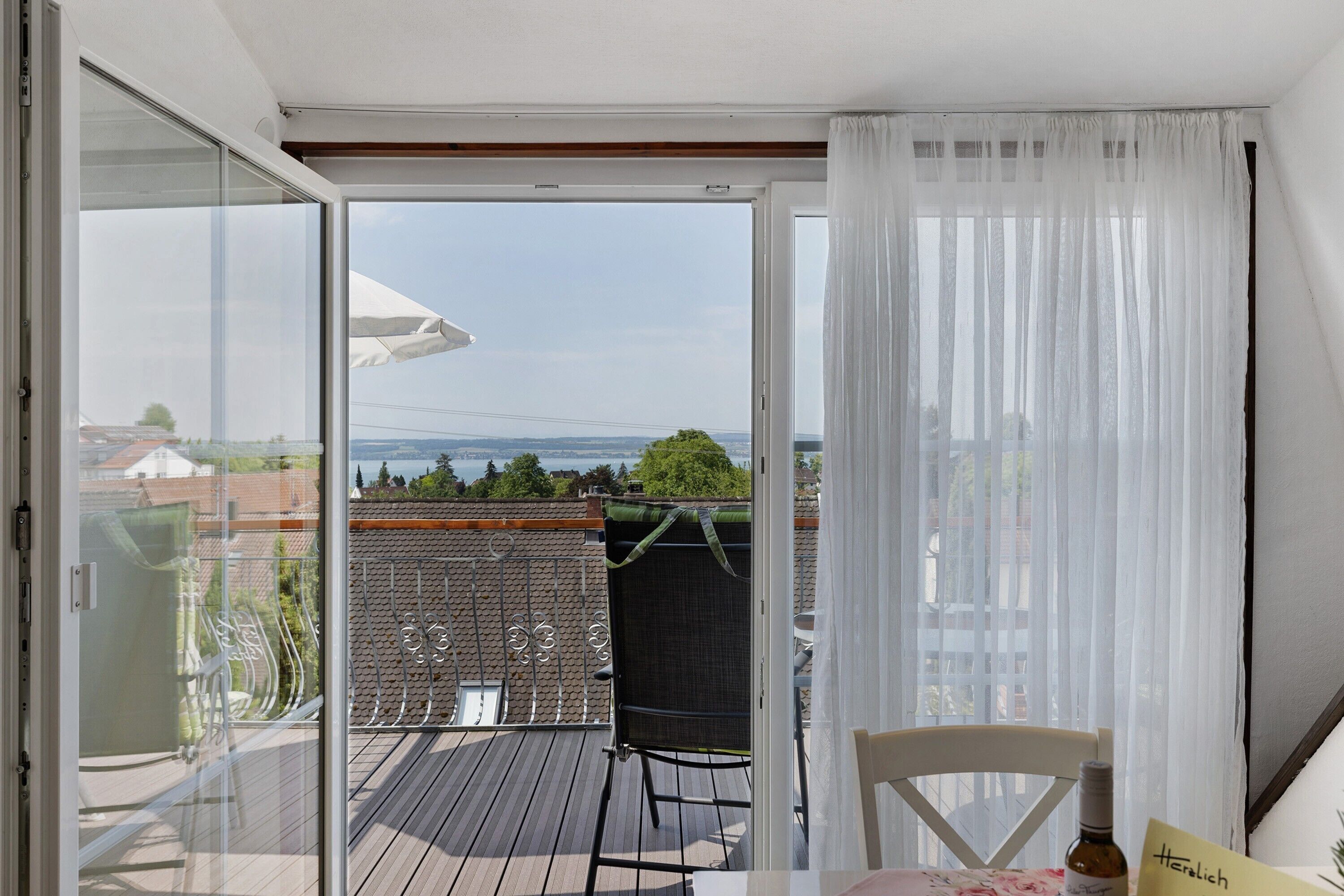 Un balcon avec une table, des chaises et une bouteille de vin.