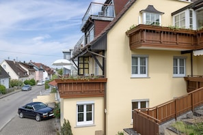 Un edificio residenziale con un balcone, una scala e un'auto parcheggiata.