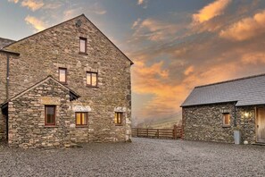 A stone building with a gravel driveway and a wooden fence. - Cottage in Lake District with Sauna & Views (Bretherdale)