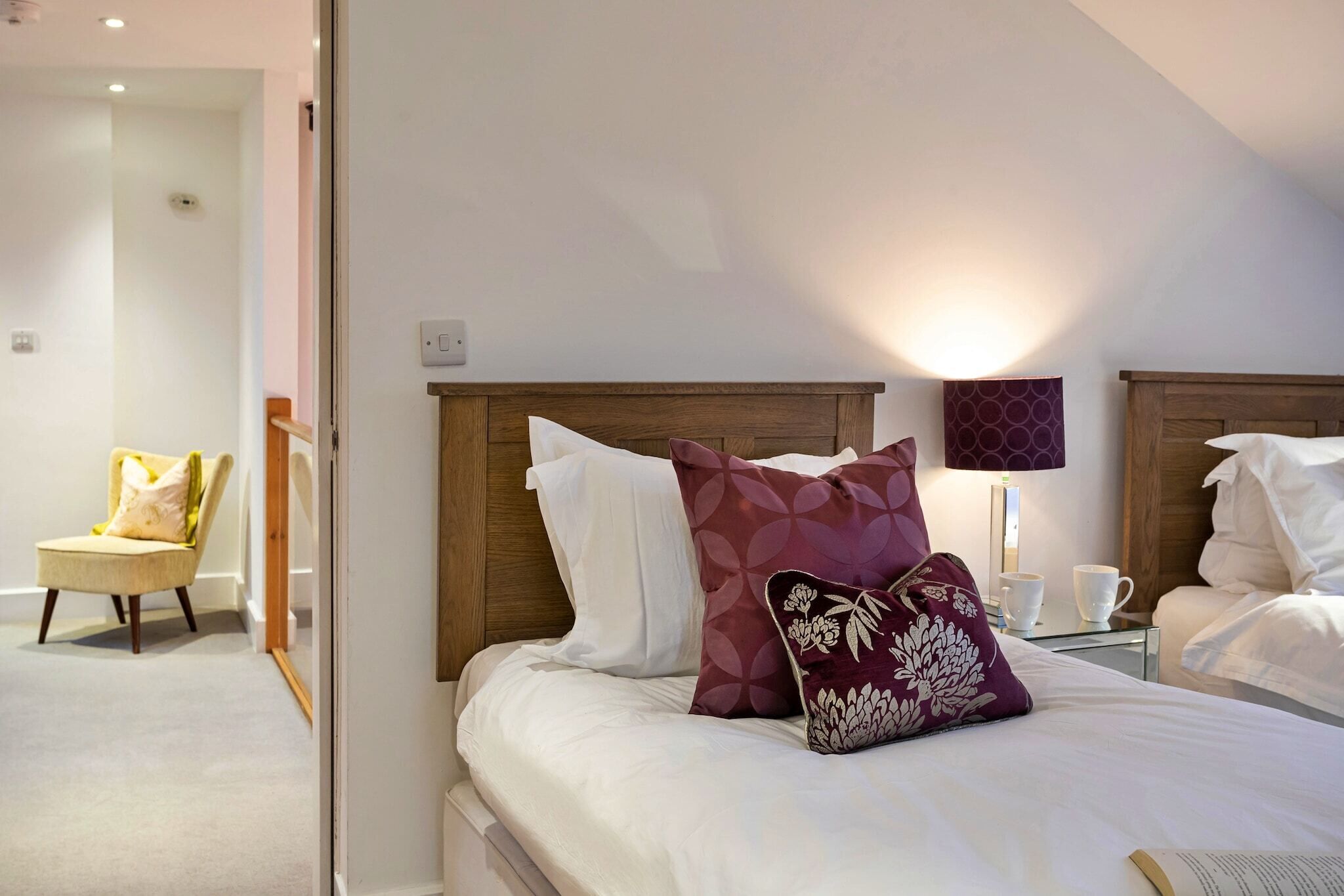 Une chambre d’hôtel avec un lit, une chaise, une table de chevet avec une lampe et un luminaire fixé au mur.