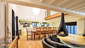 Un soggiorno moderno con camino, arredi in legno e vista sulla cucina e sull'area pranzo.