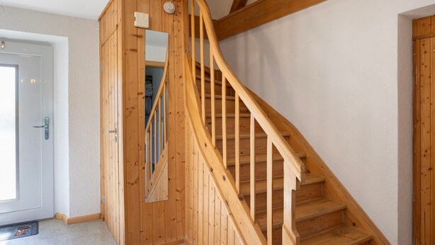 A wooden staircase with a handrail, a door with a handle, and a light switch on the wall. - Holiday Home 'Ferienhaus Kreuzbergblick' with Mountain View, Private Terrace and Wi-Fi (Hohenau)