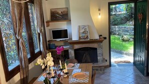 A dining area with a wooden table set for four, a fireplace, and a TV in the background.