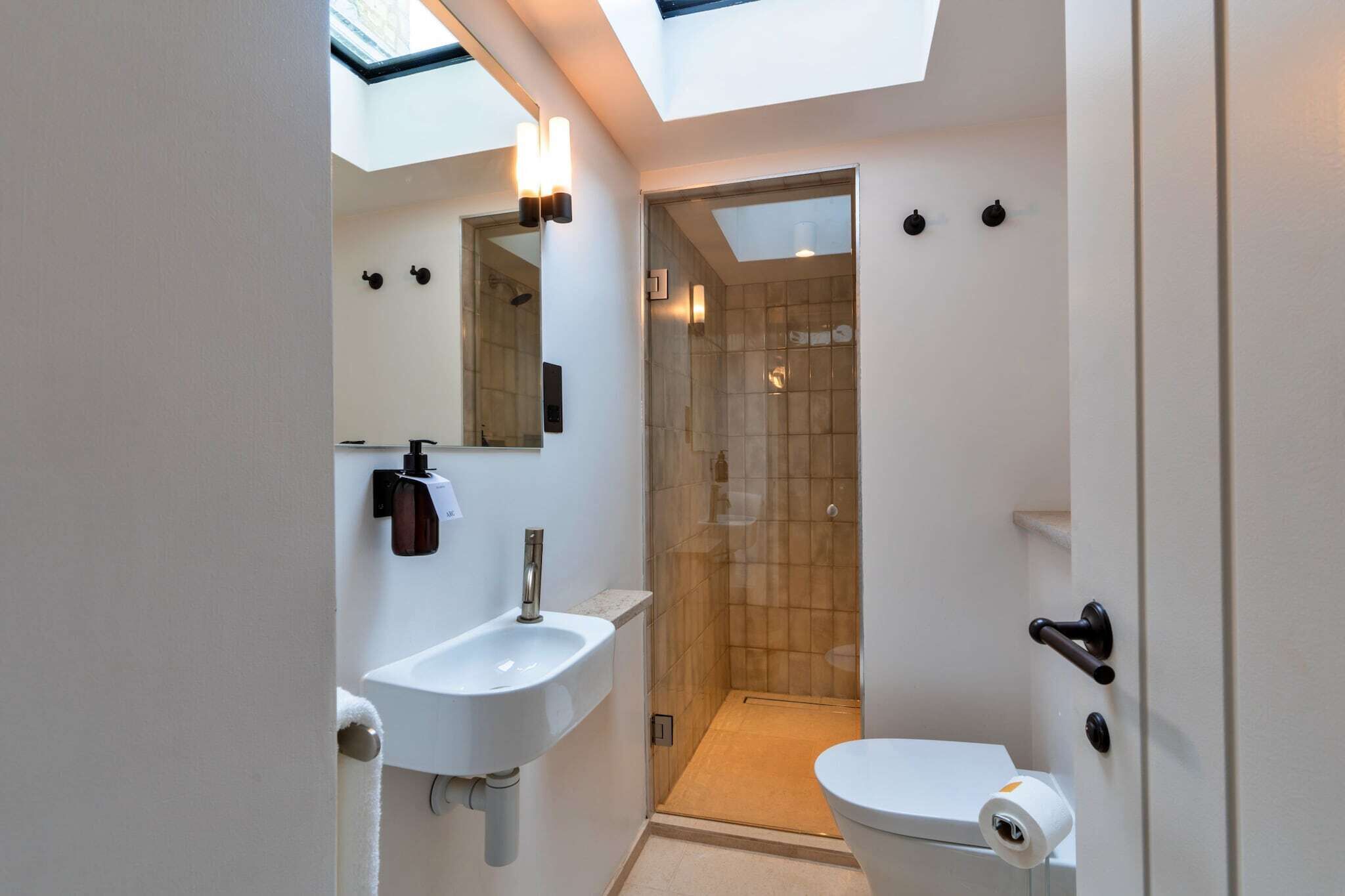 Een kleine badkamer met dakraam, douche en toilet.