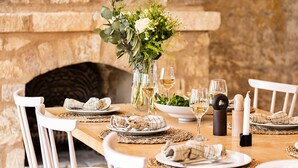 Une table à manger agrémentée de chaises blanches, d’un vase avec des plantes vertes, de verres à vin et d’un chandelier.