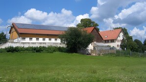 Un edificio grande con techo de paneles solares, un área cercada y un árbol en frente.