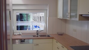 Una cocina con ventana, pileta, alacenas y horno empotrado.