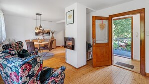Un salon comprenant un canapé, une table à manger, des chaises, un téléviseur et une porte en bois donnant sur l’extérieur.