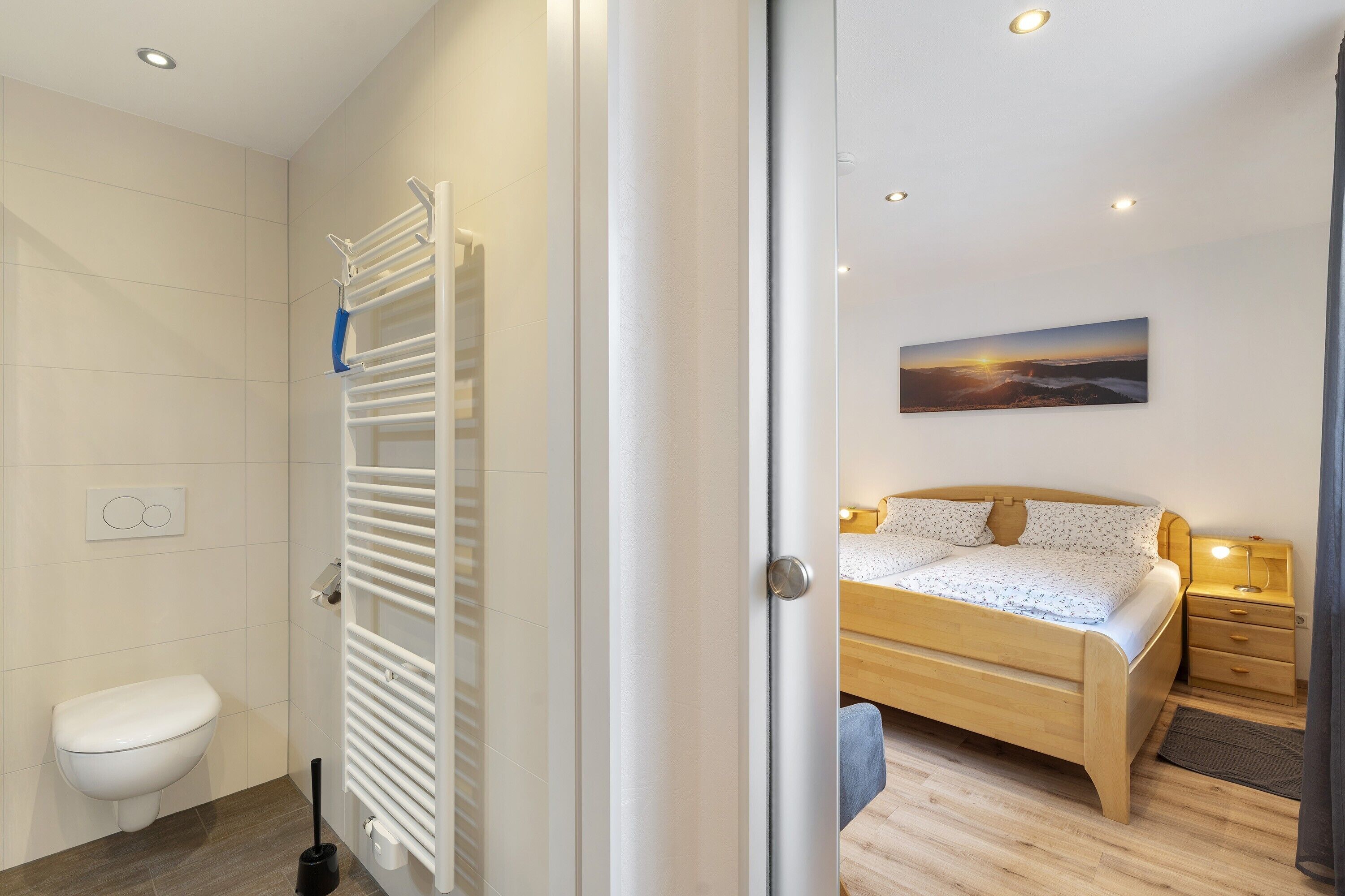 A modern bathroom with a toilet, towel rack, and a shower.