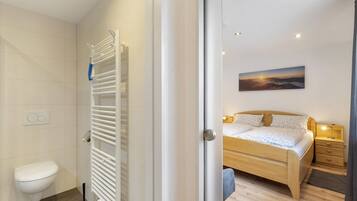 A modern bathroom with a toilet, towel rack, and a shower.