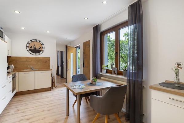 A modern kitchen with a wooden countertop, a dining area with a table and chairs, and a large window with curtains.