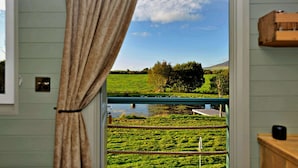 A room with a view of a green field, a small pond, and a bench. - Shepherd’s Hut on Llŷn Peninsula by Private Lake (Pwllheli)