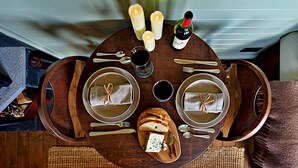 A dining table set with plates, cutlery, bread, cheese, and wine, suggesting a meal setting. - Shepherd’s Hut on Llŷn Peninsula by Private Lake (Pwllheli)