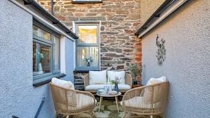 A cozy outdoor seating area with wicker chairs, a sofa, and a small table with a vase of flowers.