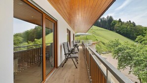 A balcony with a view of a green hillside, wooden ceiling, and modern chairs. - Holderstanzenhof: Apartment 'Talblick' with Mountain View, Private Balcony and Wi-Fi (Bad Peterstal-Griesbach)