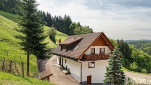 A house with a sloped roof, a balcony, and a paved driveway. - Holderstanzenhof: Apartment 'Talblick' with Mountain View, Private Balcony and Wi-Fi (Bad Peterstal-Griesbach)