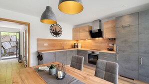 A modern kitchen with grey cabinets, a wooden countertop, and pendant lighting. - Holderstanzenhof: Apartment 'Talblick' with Mountain View, Private Balcony and Wi-Fi (Bad Peterstal-Griesbach)