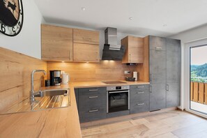 A modern kitchen with wooden cabinets, a stainless steel sink, and an oven.