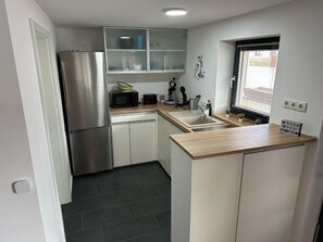 A compact kitchen with a stainless steel refrigerator, a microwave, a coffee maker, and a sink.