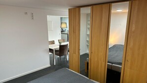 Un dormitorio con cama, armario, zona de comedor y una lámpara.