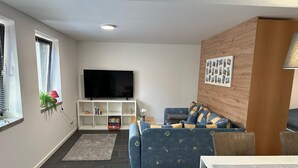 Una sala de estar con televisor, sofá y una mesita.