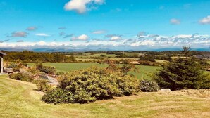 A rural landscape with a house and a view of rolling hills and distant mountains. - Shepherd's Hut on Llŷn Peninsula, Near Snowdonia (Pwllheli)