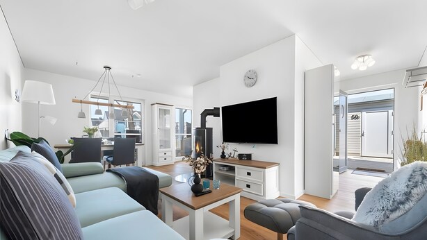 A modern living room with a sofa, armchair, and TV. There is a dining area with chairs and a table. - Holiday Apartment 'Maltes' with Sea View, Private Terrace and Wi-Fi (Kappeln)
