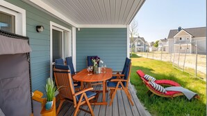 A covered patio with a wooden table and chairs, a small potted plant, and a red lounge chair. - Holiday Apartment 'Maltes' with Sea View, Private Terrace and Wi-Fi (Kappeln)