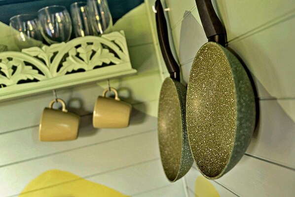 A kitchen with a hanging pot rack, a knife block, and a decorative white shelf.
