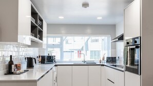 Una cocina moderna con armarios blancos, un ventanal grande y un horno empotrado.