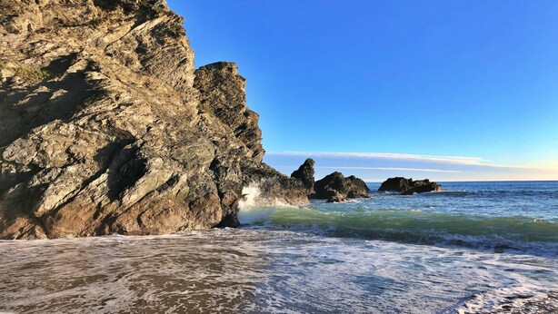 Una costa rocosa con olas rompiendo sobre la orilla.