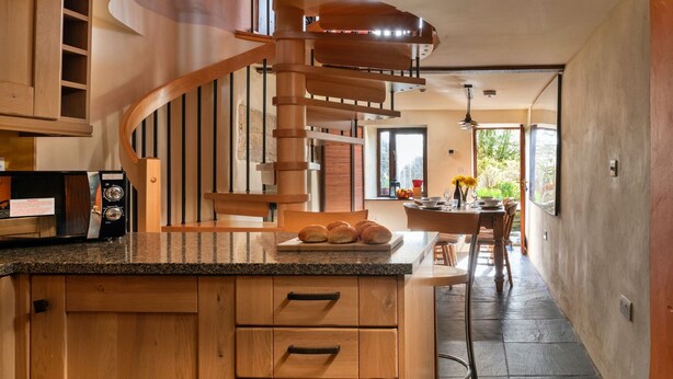 Una cocina con una isla de madera, estufa empotrada y una escalera en espiral.