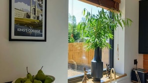 A kitchen with a window, a bowl of pears, a potted plant, a rabbit figurine, and a toaster.