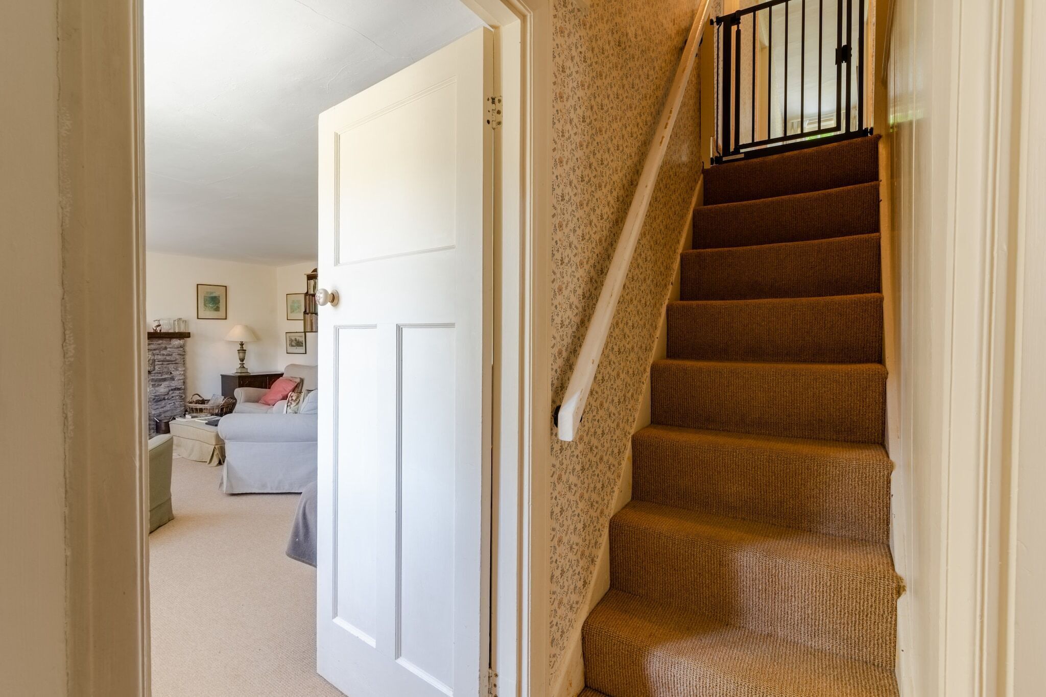 A carpeted staircase with a handrail, leading to a room with a bed and a lamp.