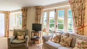 Een woonkamer met een bank, fauteuil en een televisie op een dressoir.