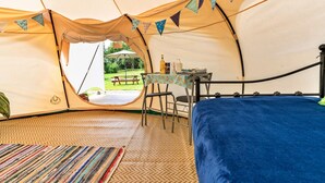 Ein Zelt mit Bett, Tisch und Blick ins Freie.