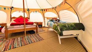 Una tenda amb dos llits, cadascun amb estructura de fusta i roba de llit colorida.