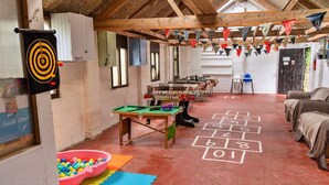A rustic room with a dartboard, a hopscotch game, a pool table, and colorful mats on the floor. - Bell Tent in Devon with Countryside Views (Ilfracombe)