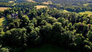 Vista aérea de un paisaje rural con una extensa propiedad rodeada de densos bosques y colinas ondulantes.