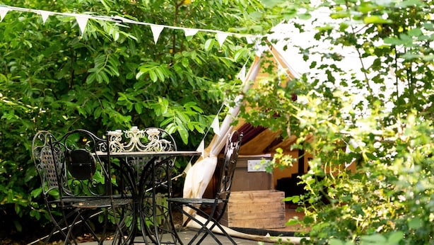 An outdoor dining area with a metal table and chairs, surrounded by lush greenery. - Woodland Pod near Highclere Castle (Woolton Hill)