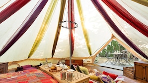 A cozy interior of a tent with a bed, a table with tea sets, and a view of the outdoors. - Woodland Pod near Highclere Castle (Woolton Hill)
