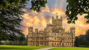 A large, historic building with multiple towers and a well-maintained lawn in front. - Woodland Pod near Highclere Castle (Woolton Hill)
