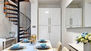Un espace repas moderne avec une table en marbre, des touches de bleu et d’or, et un escalier en colimaçon.