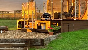 Un espace cuisine extérieur moderne, doté d’un barbecue, de sièges et d’une grande baie vitrée.