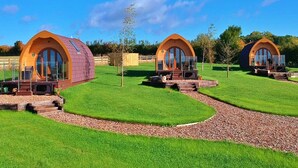 Une rangée de cabines modernes en forme de dôme, dotées de grandes fenêtres, est aménagée sur une pelouse bien entretenue, avec un chemin de gravier qui y mène.